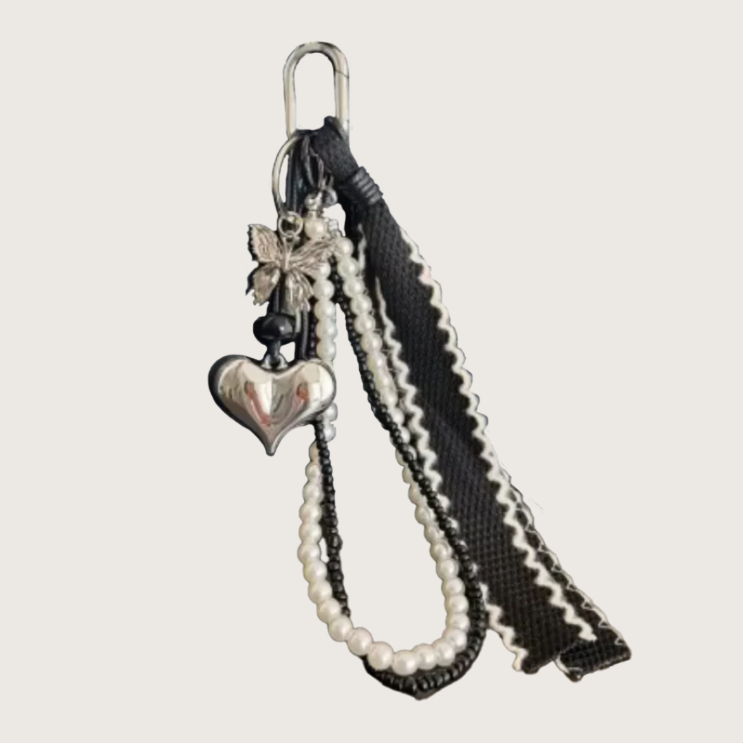 Keychain or bag charm with silver heart charm, pearl extension, and decorative strap.