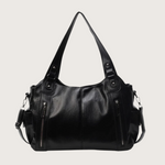 Black leather handbag with multiple zippers on a white background