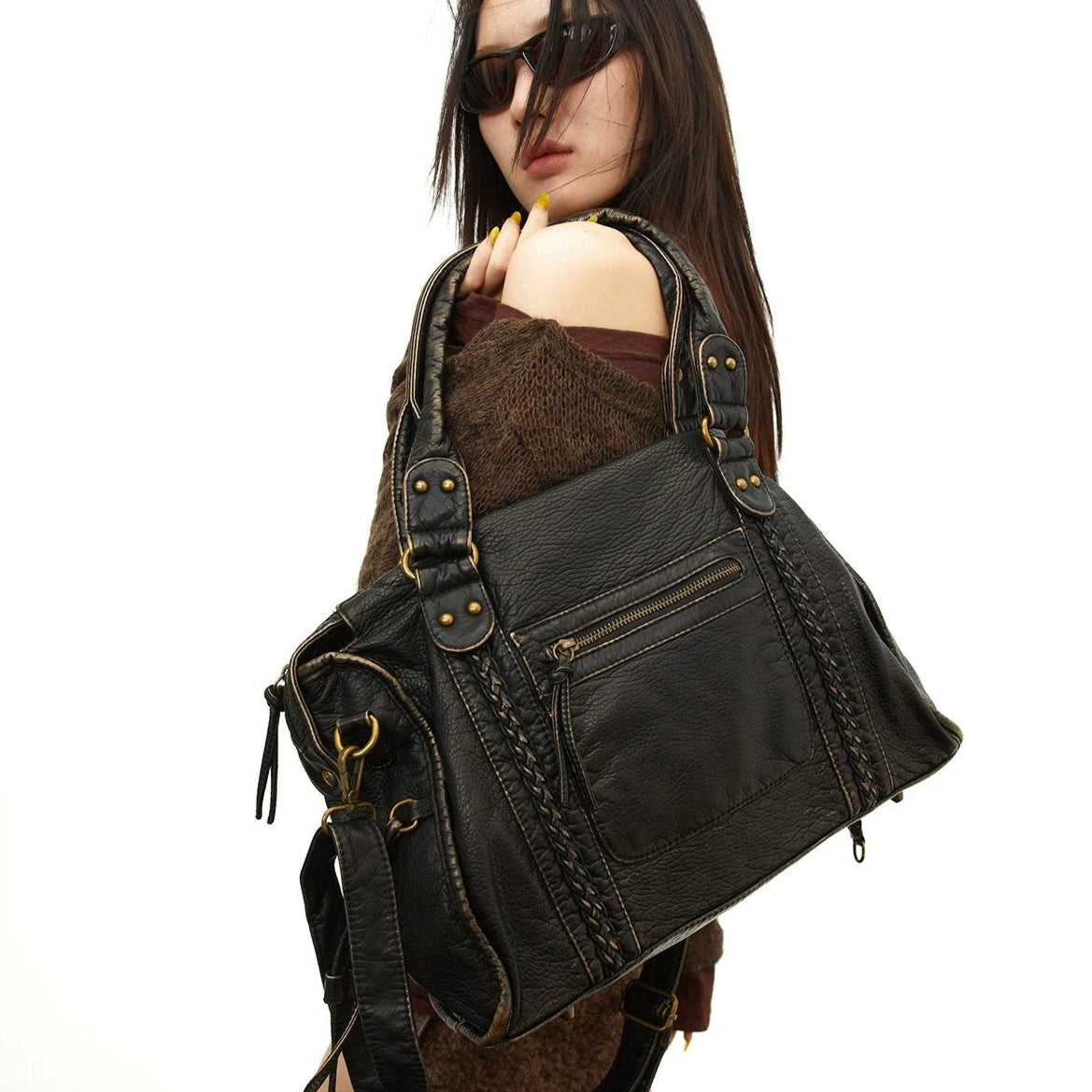 Woman wearing a large black leather bag on a white background